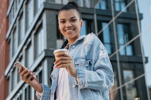 Young adult standing outside building with cell phone in hand